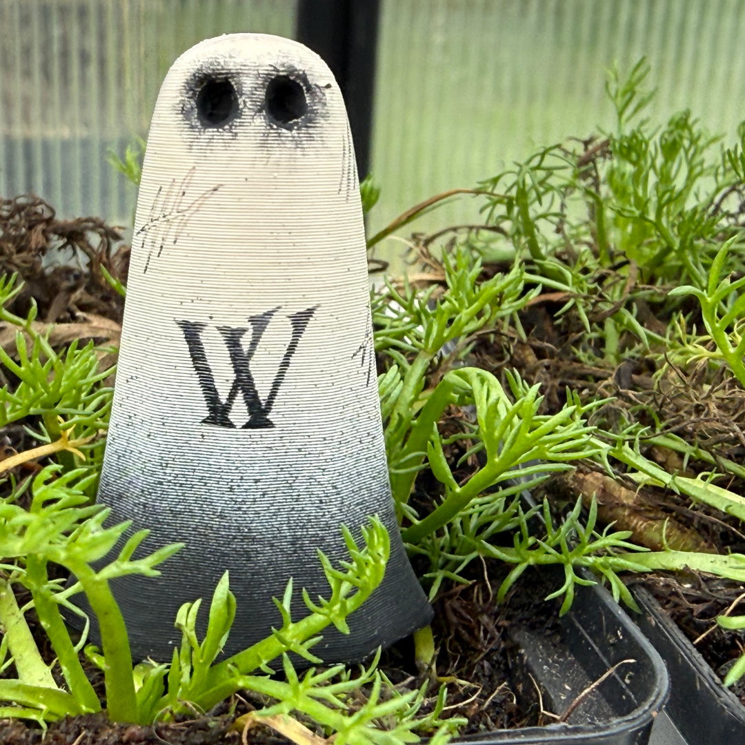 An ivory and black ghost figurine by The Nordic Ghost Merchants. The ghost is engraved with witch marks.