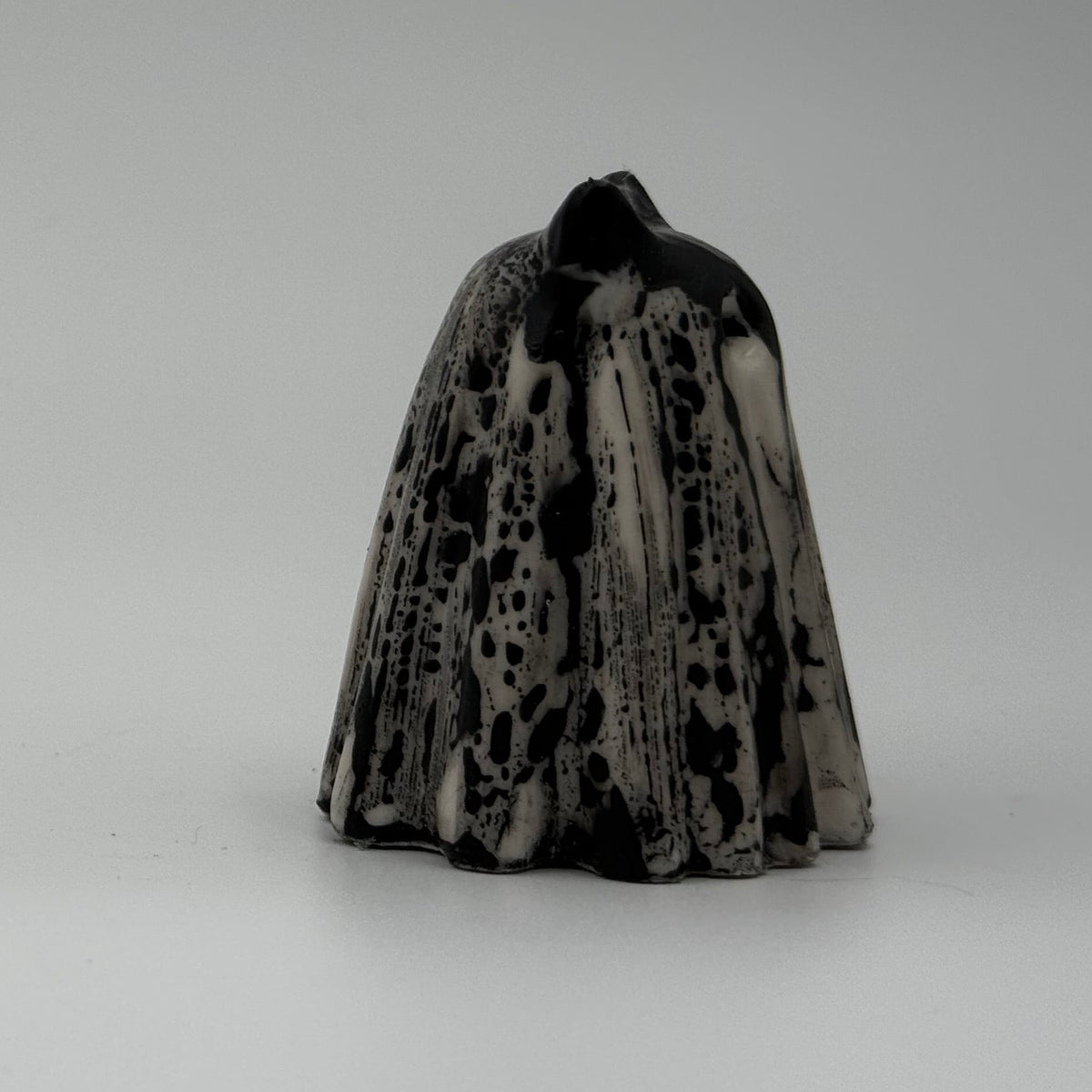 A small black and white ghost cat figurine handmade by The Nordic Ghost Merchants. The pattern resembles rain running down a window. Side view