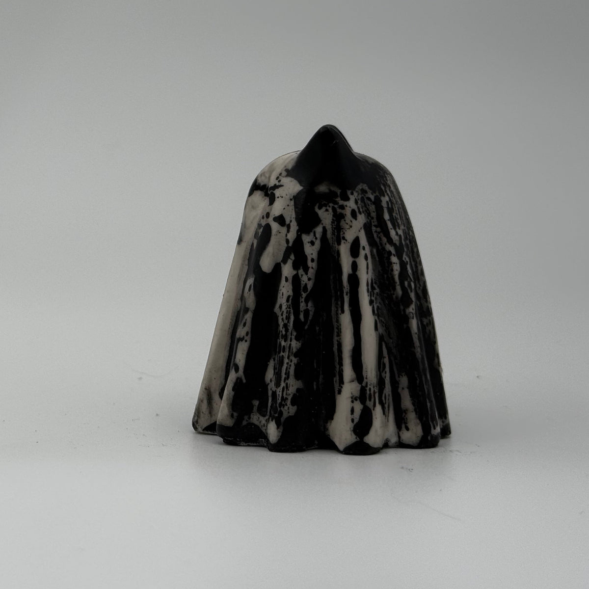 A small black and ivory coloured ghost cat figurine by The Nordic Ghost Merchants. Side view