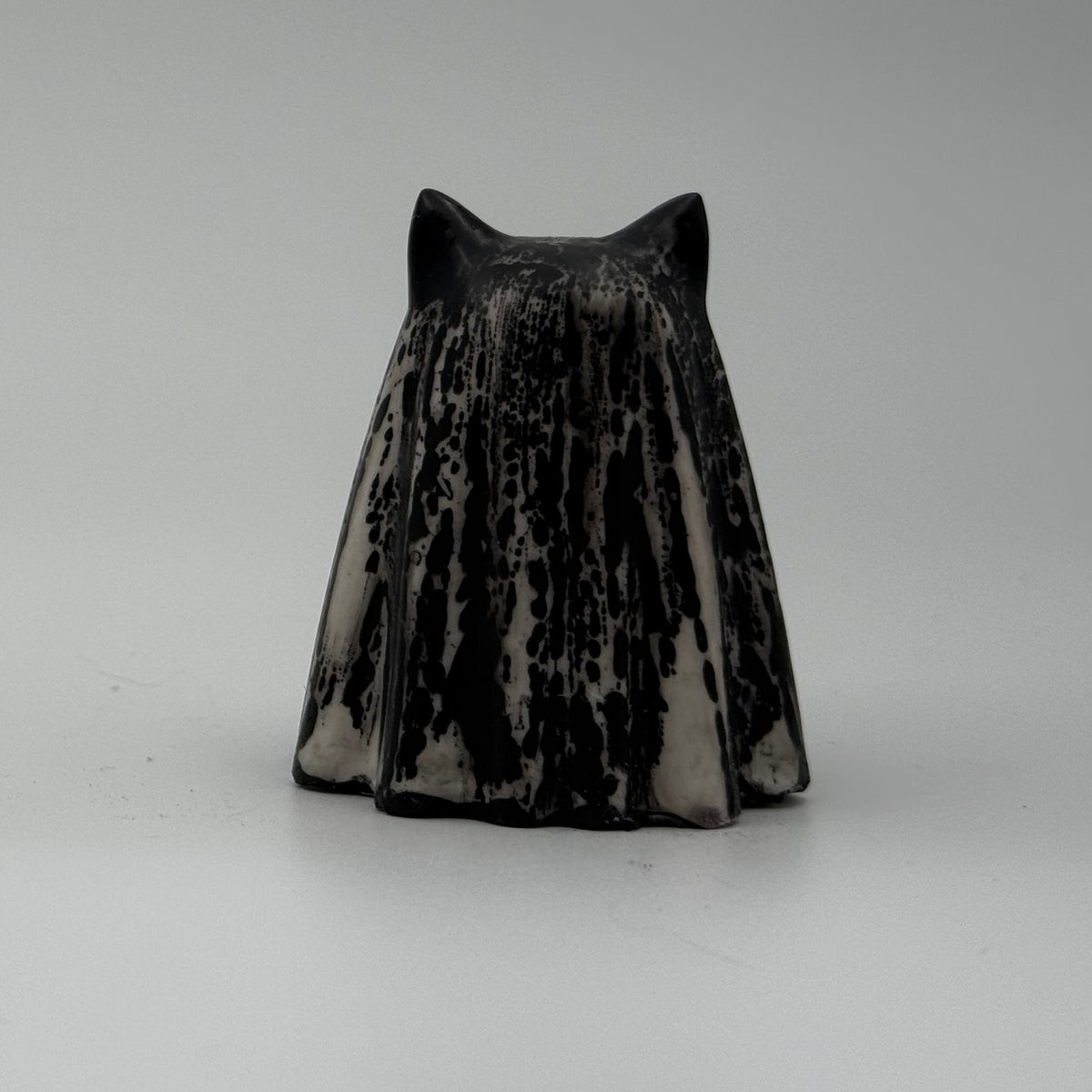 A small black and ivory coloured ghost cat figurine by The Nordic Ghost Merchants. Rear view