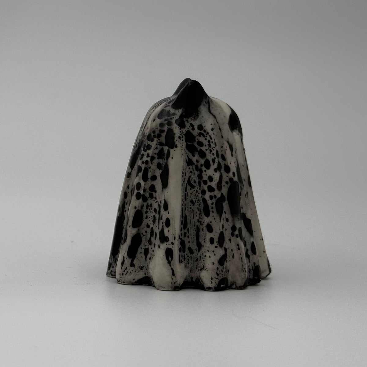 An ivory coloured ghost cat figurine with dramatic black, bark like patterning, by The Nordic Ghost Merchants. Side view.