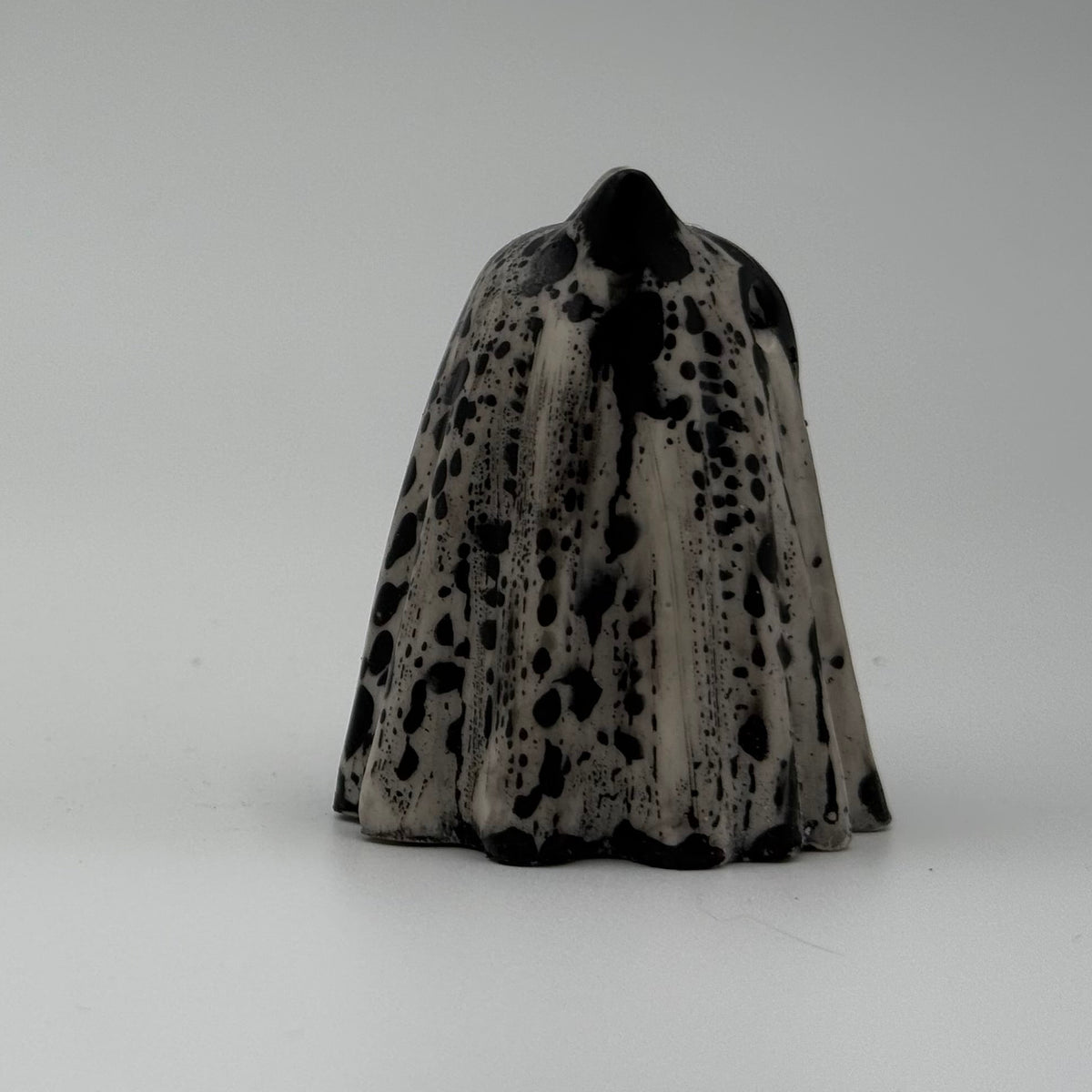 An ivory ghost cat ornament with dramatic black, bark link patterning, made by The Nordic Ghost Merchants. Side view.
