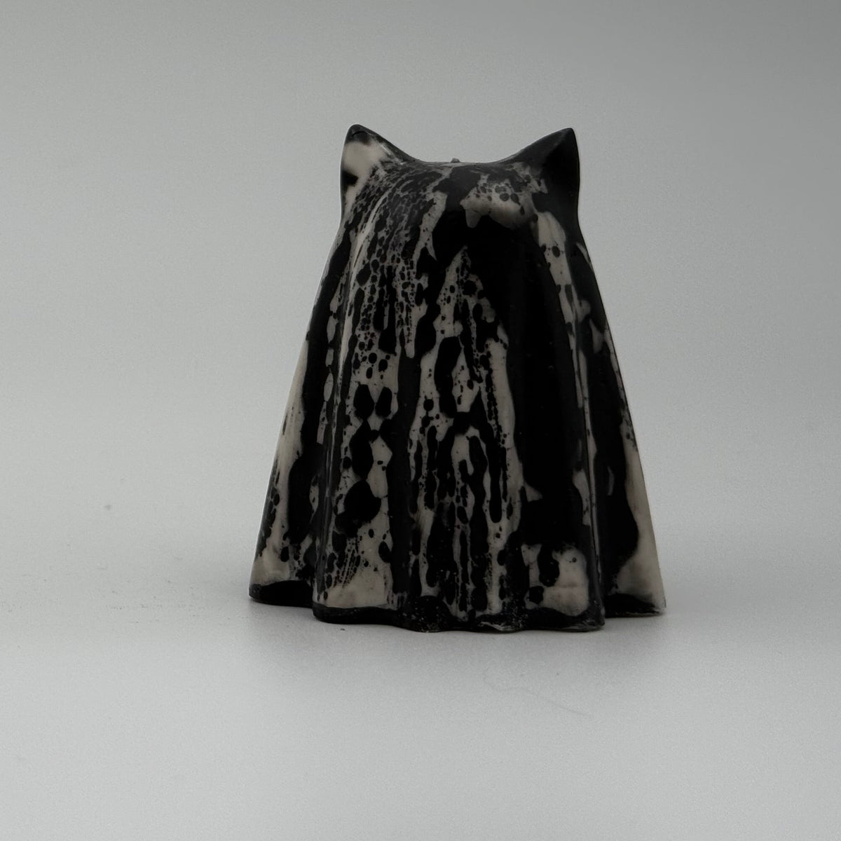 An ivory coloured ghost cat figurine with dramatic, black, bark like patterning, made by The Nordic Ghost Merchants. Rear view