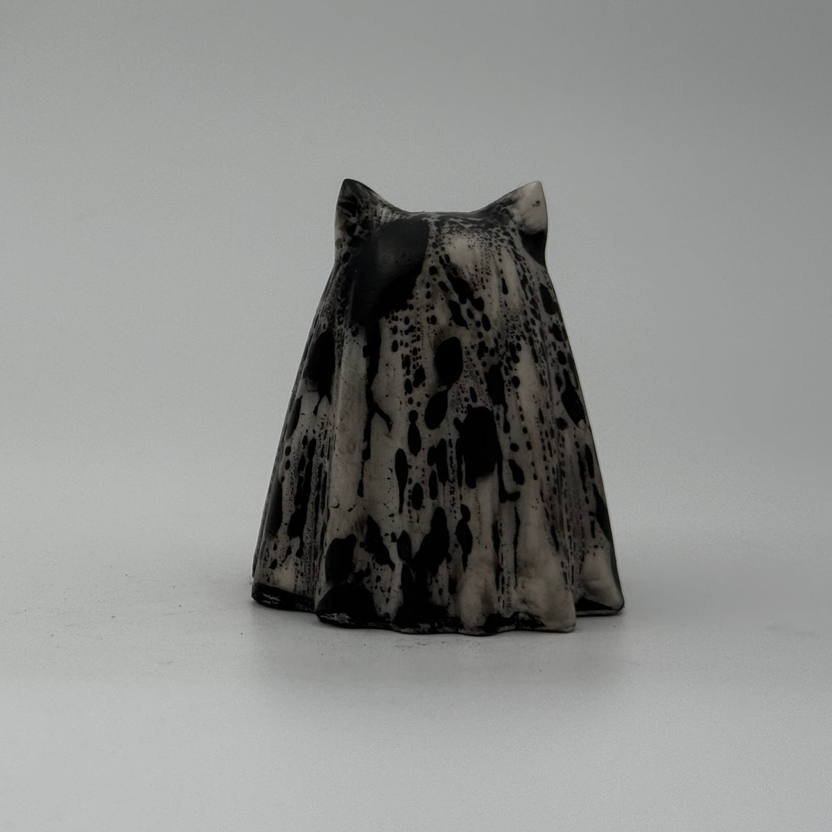 A small white and black ghost cat figurine by The Nordic Ghost Merchants. Rear view