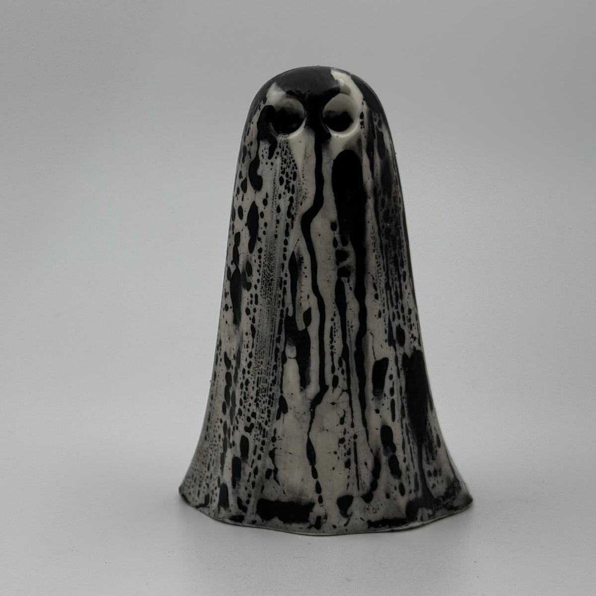 An ivory coloured ghost figurine with black, bark like patterning, made by The Nordic Ghost Merchants. Front view.