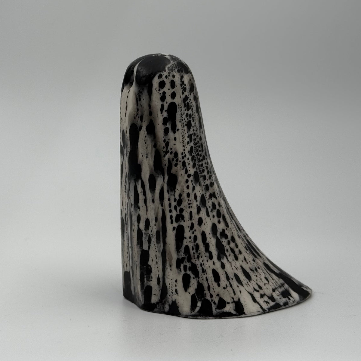 An ivory coloured ghost figurine with dramatic black bark like patterns, made by The Nordic Ghost Merchants. Side view