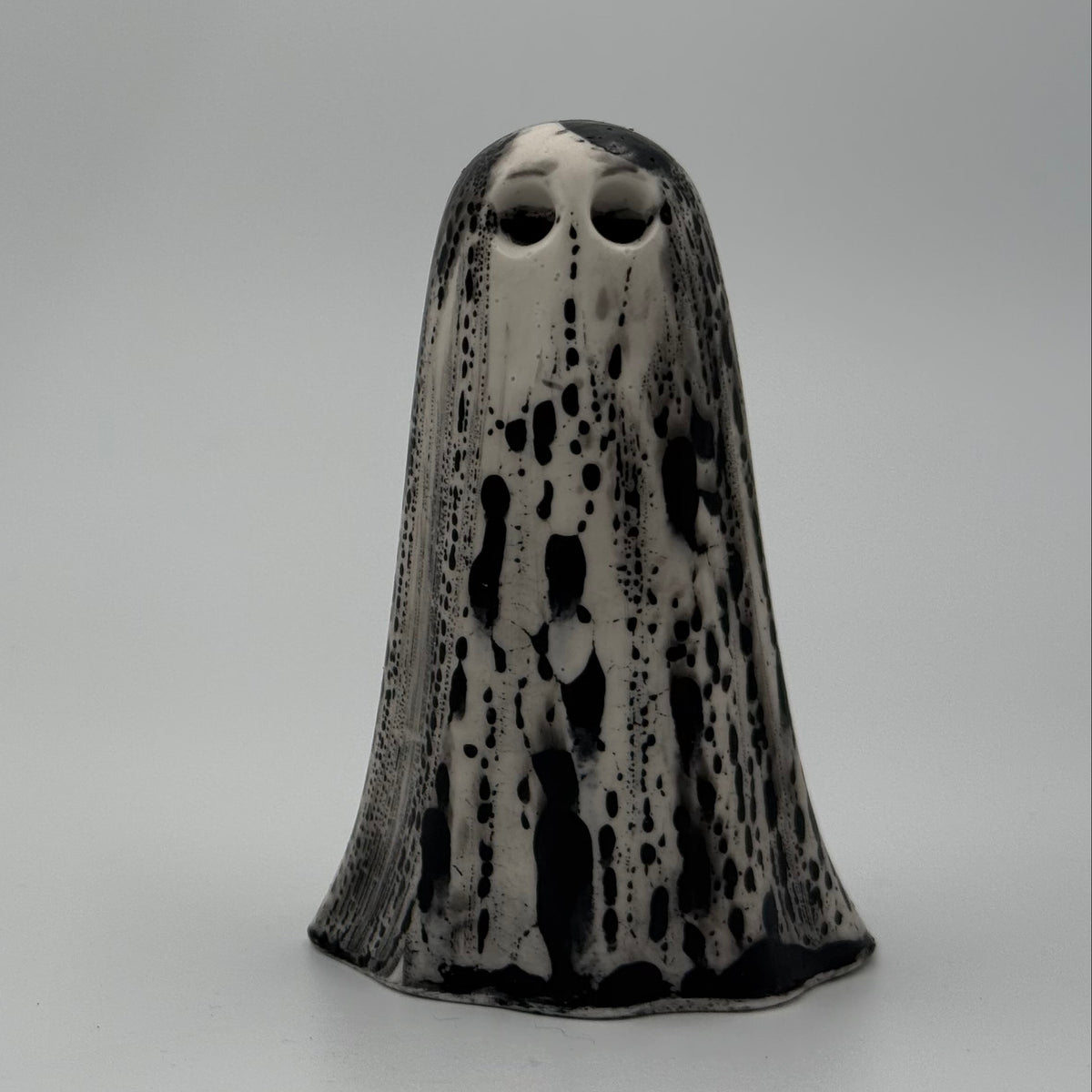 An ivory ghost figurine with dramatic black, bark like patterning, made by The Nordic Ghost Merchants. Front view.