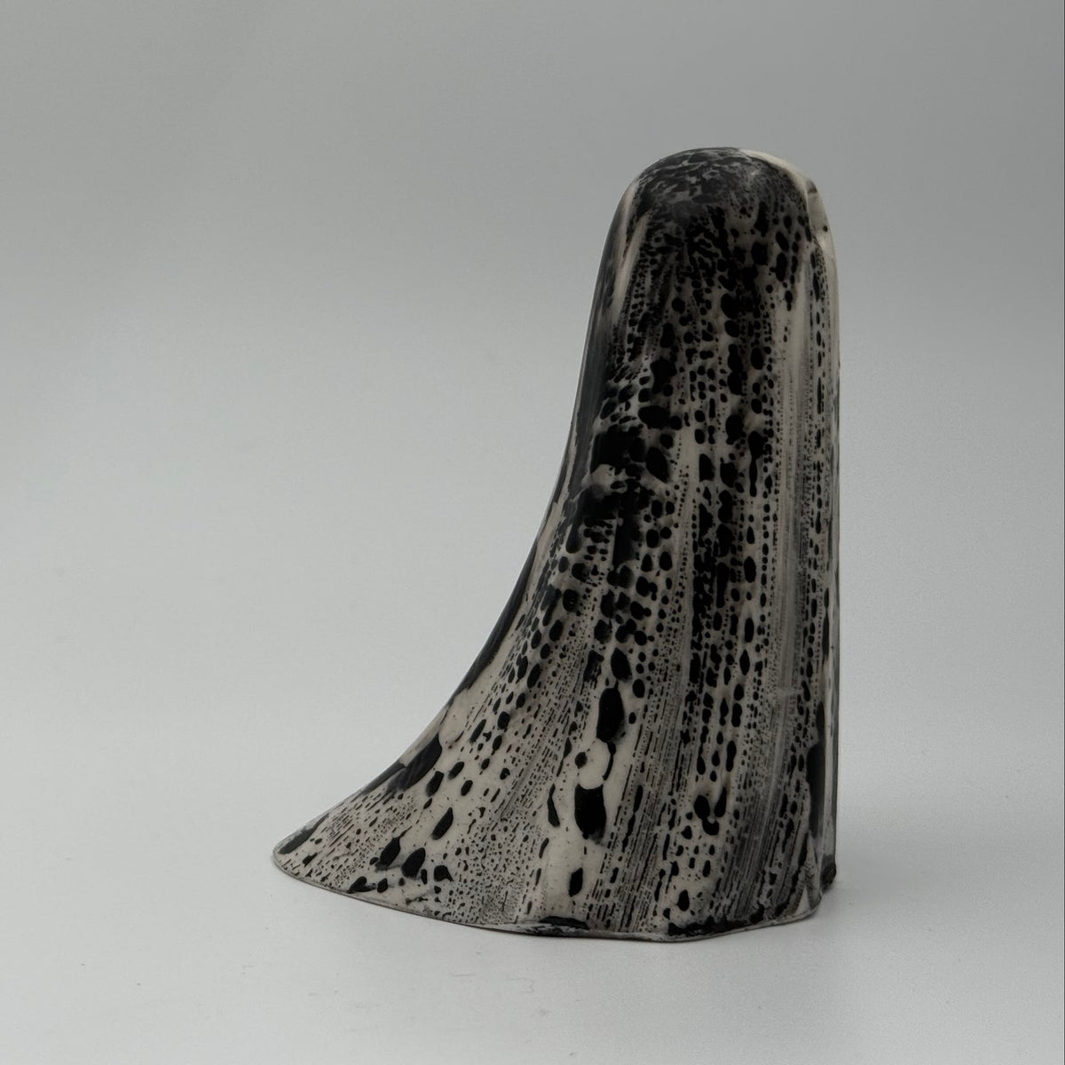 An ivory ghost figurine with dramatic black, bark like patterning, made by The Nordic Ghost Merchants. Side view.