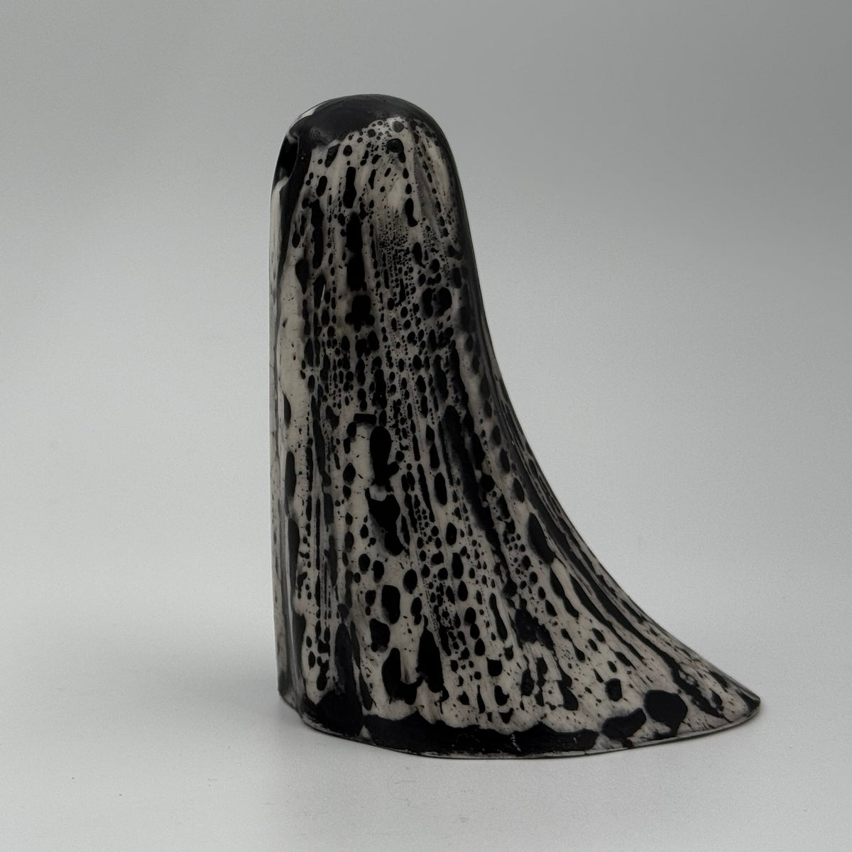 An ivory coloured ghost ornament with dramatic black, bark like patterning, made by The Nordic Ghost Merchants. Side view.