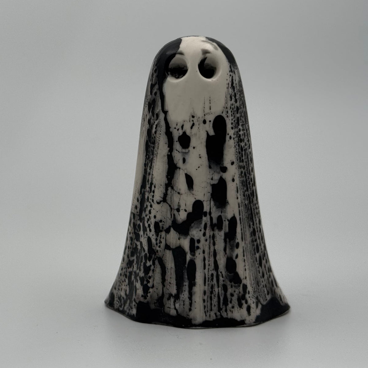 An ivory ghost ornament with dramatic black, bark like patterning, made by The Nordic Ghost Merchants. Front view