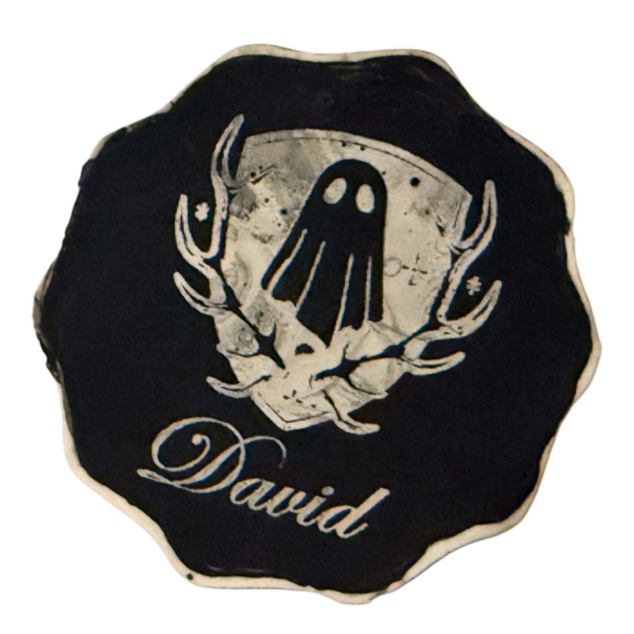 The base of a handmade ghost figurine by The Nordic Ghost Merchants. It's engraved with the brand logo - a crest - and the ghost's name