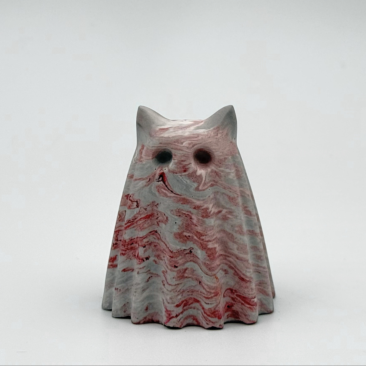A small grey and white marbled ghost cat figurine, hand made by The Nordic Ghost Merchants. The ghost has red ripples running throughout.