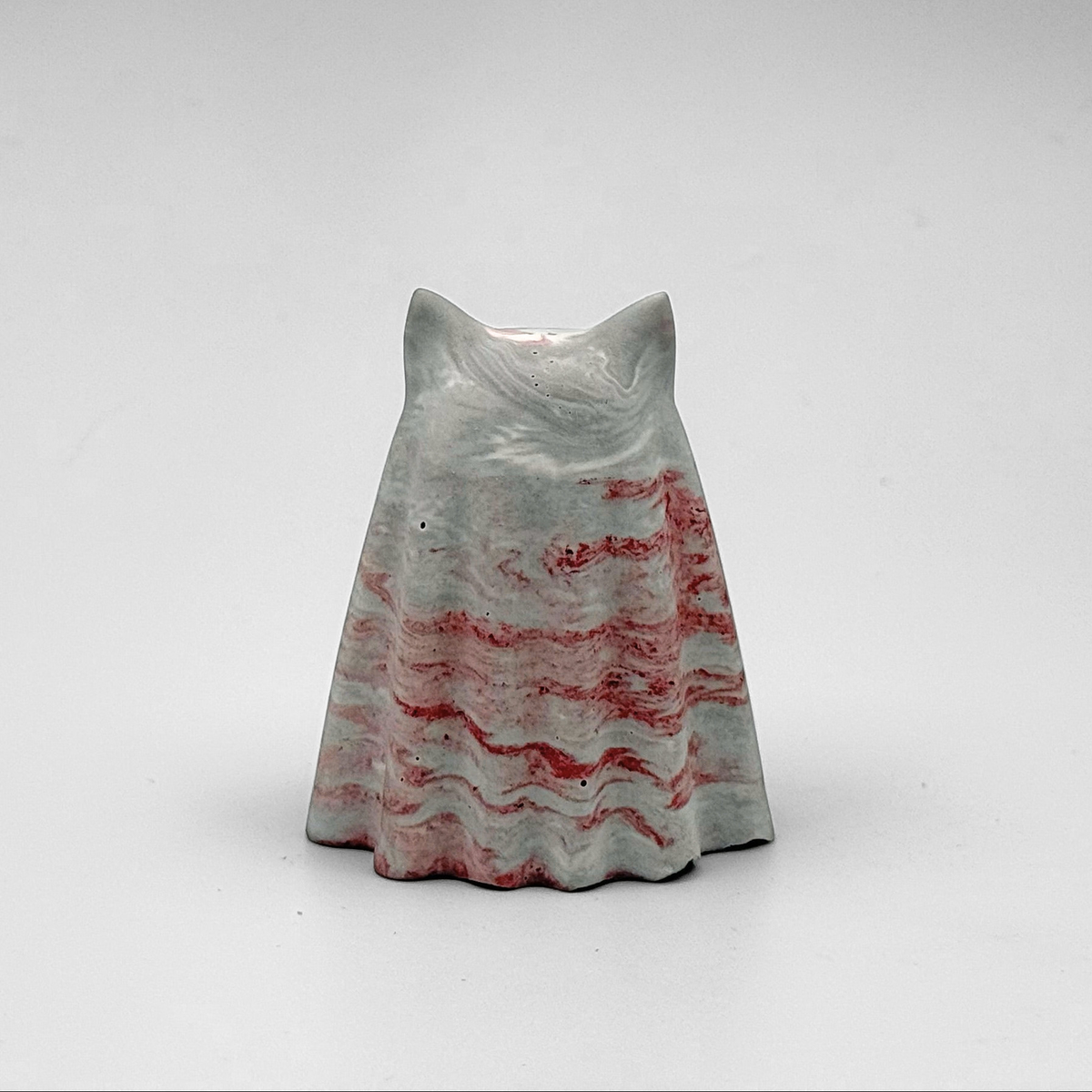 A small grey and white marbled ghost cat figurine, hand made by The Nordic Ghost Merchants. The ghost has red ripples running throughout.