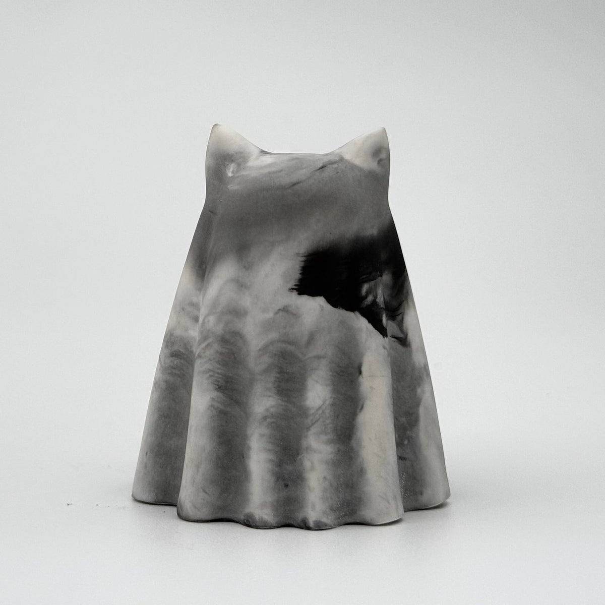 A grey and white handmade ghost figurine by The Nordic Ghost Merchants. The colours are smoky or fog-like. Rear view on a grey studio background.