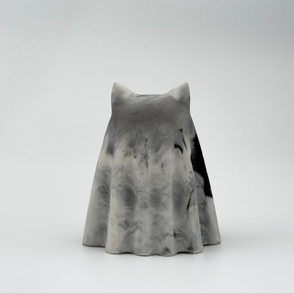 A small grey and white ghost cat figurine, inspired by foggy mornings and made by The Nordic Ghost Merchants. Rear view