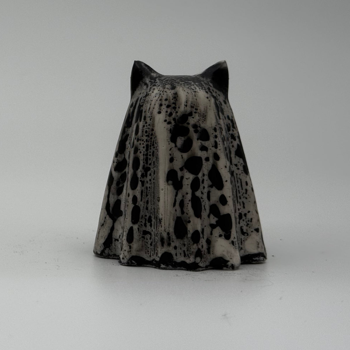 A small black and white ghost cat figurine made by The Nordic Ghost Merchants. Rear view.