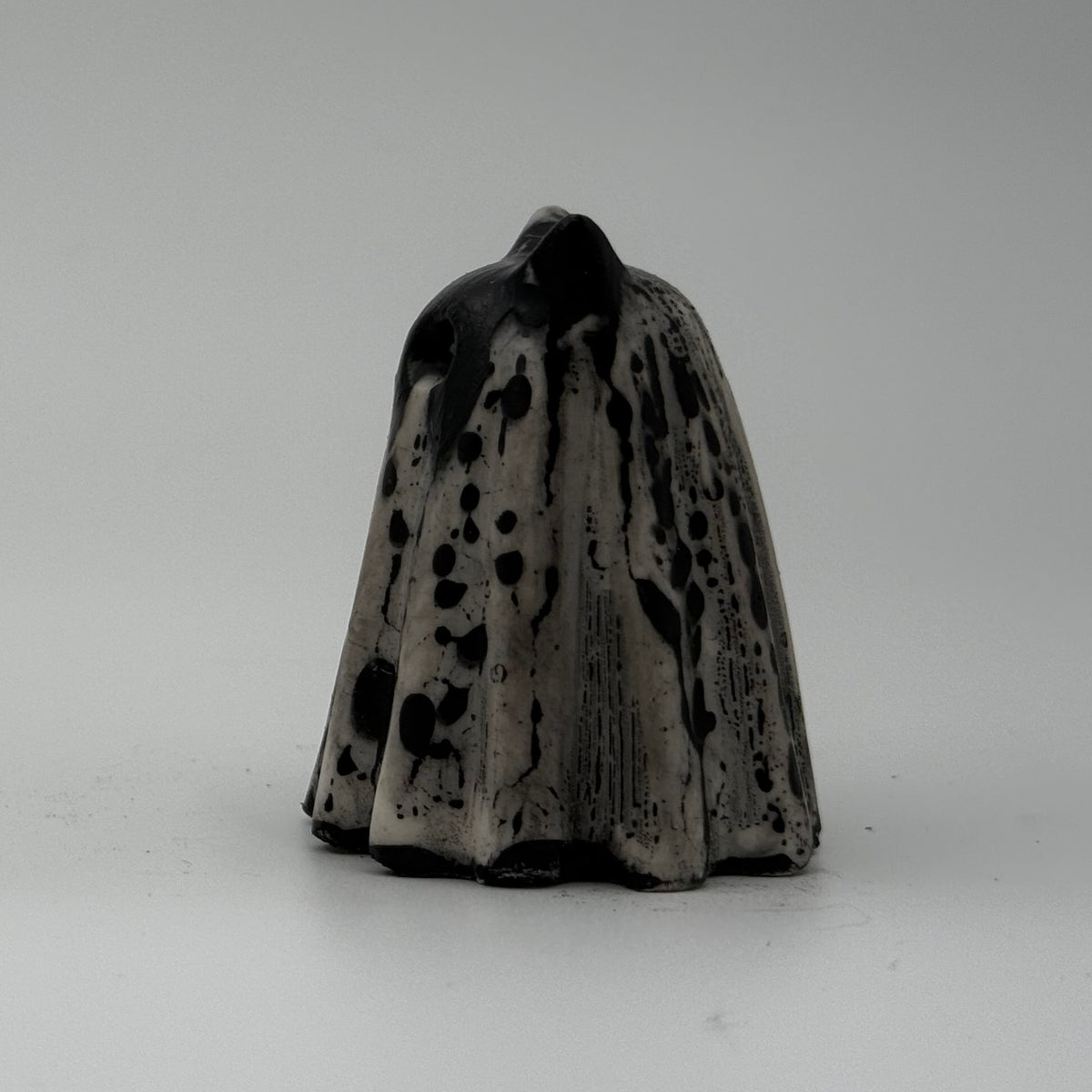 A small black and white ghost cat figurine made by The Nordic Ghost Merchants. Side view.