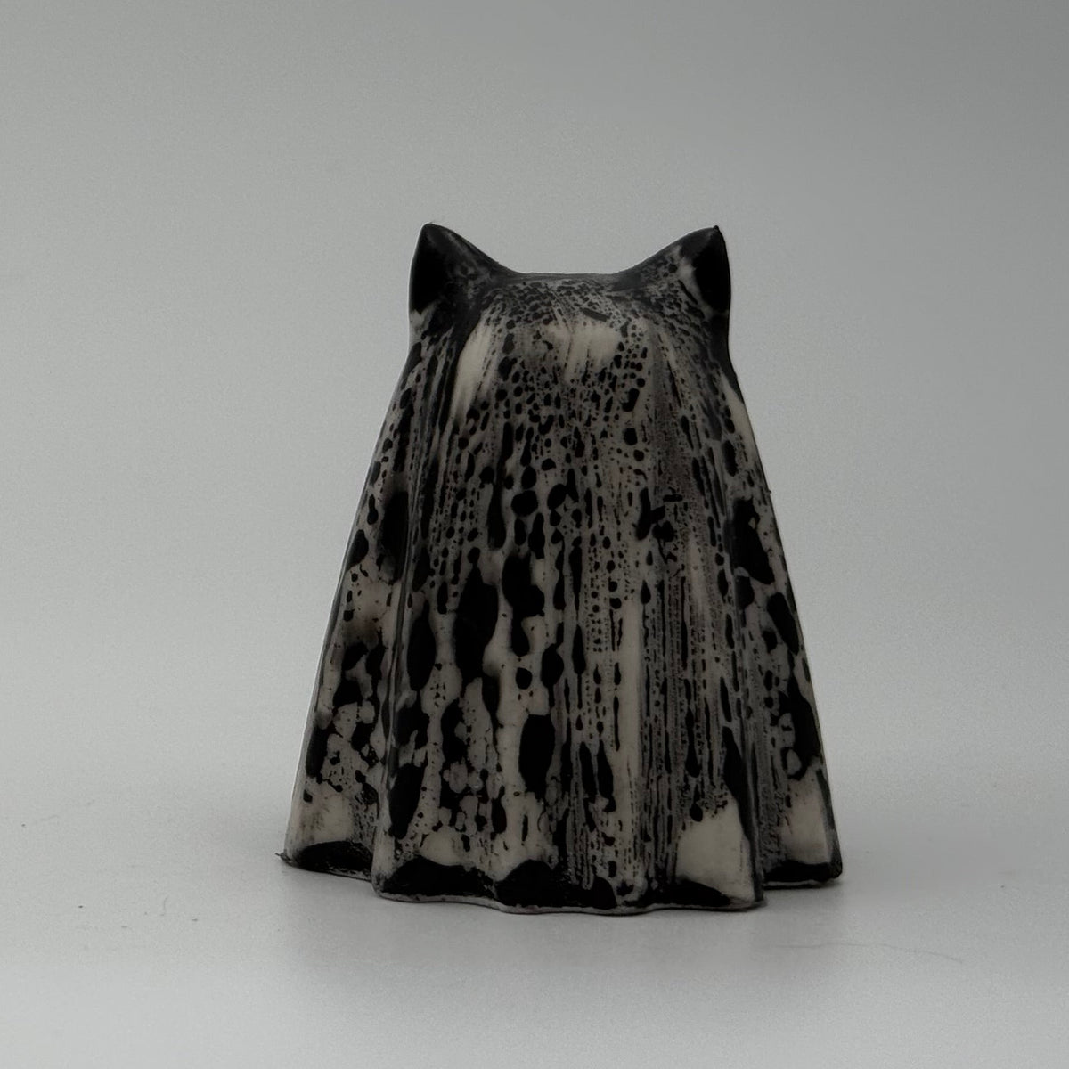 A small black and white ghost cat figurine handmade by The Nordic Ghost Merchants. The pattern resembles rain running down a window. Rear view