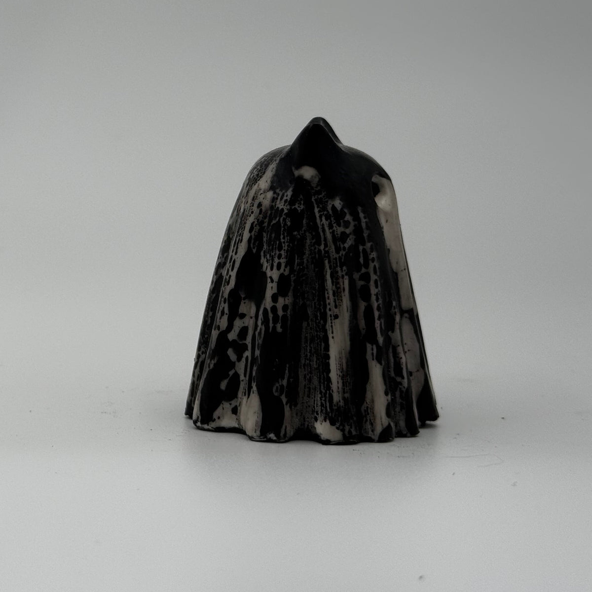 A small black and white ghost cat figurine made by The Nordic Ghost Merchants. The pattern resembles bark. Side view.