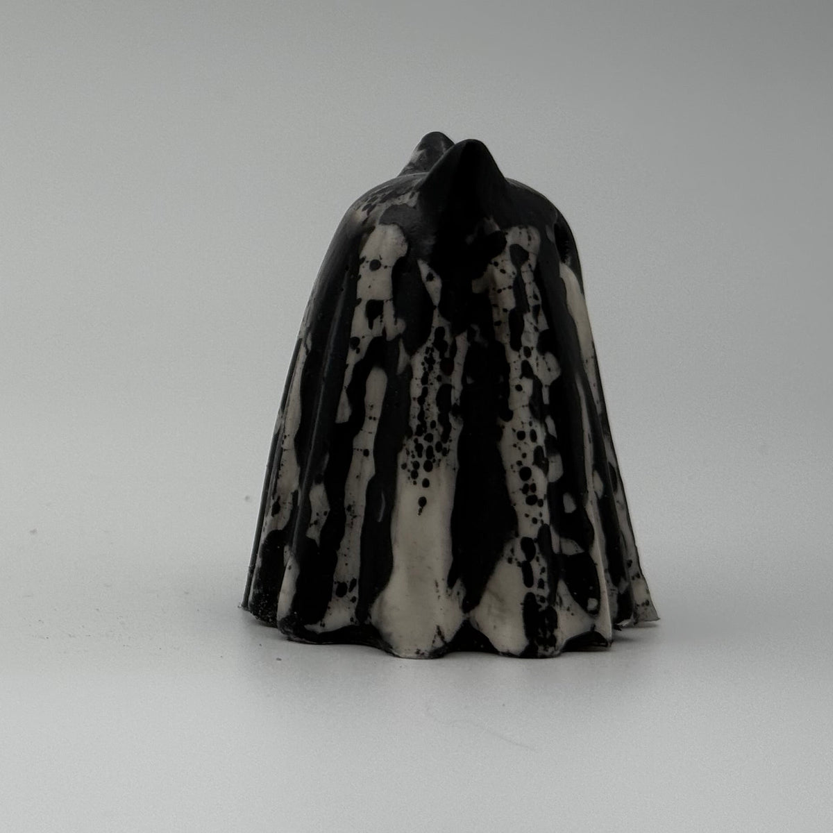 An ivory coloured ghost cat figurine with dramatic, black, bark like patterning, made by The Nordic Ghost Merchants. Side view
