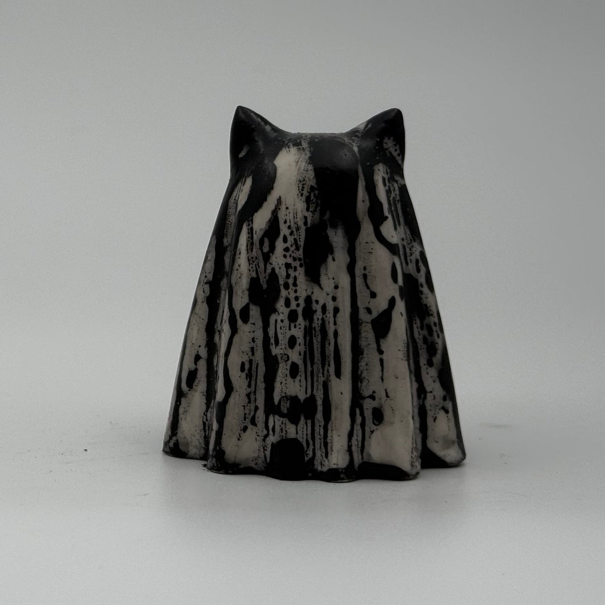 A small white and black coloured ghost cat figurine made by The Nordic Ghost Merchants. Rear view