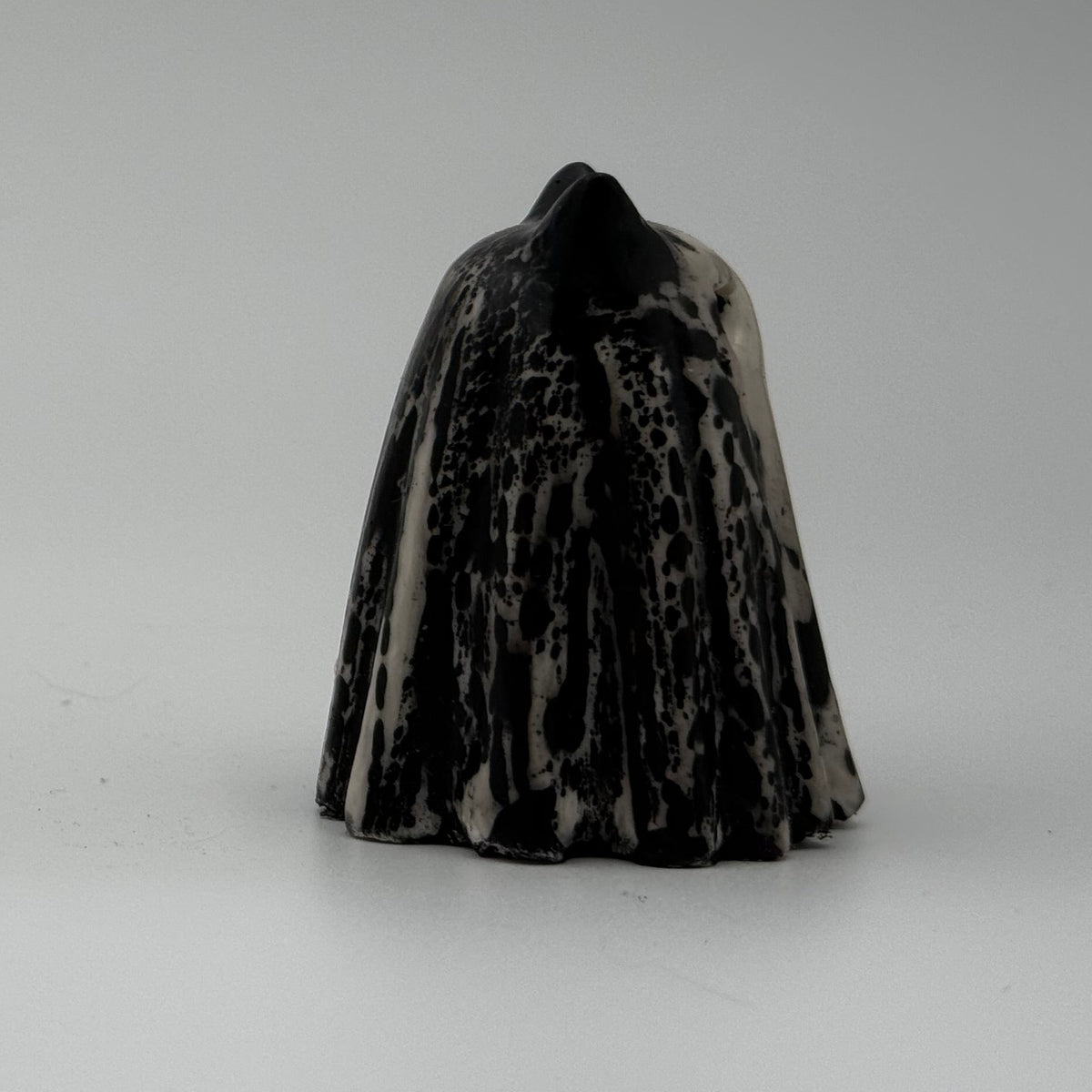 A small black and ivory coloured ghost cat figurine by The Nordic Ghost Merchants. Side view