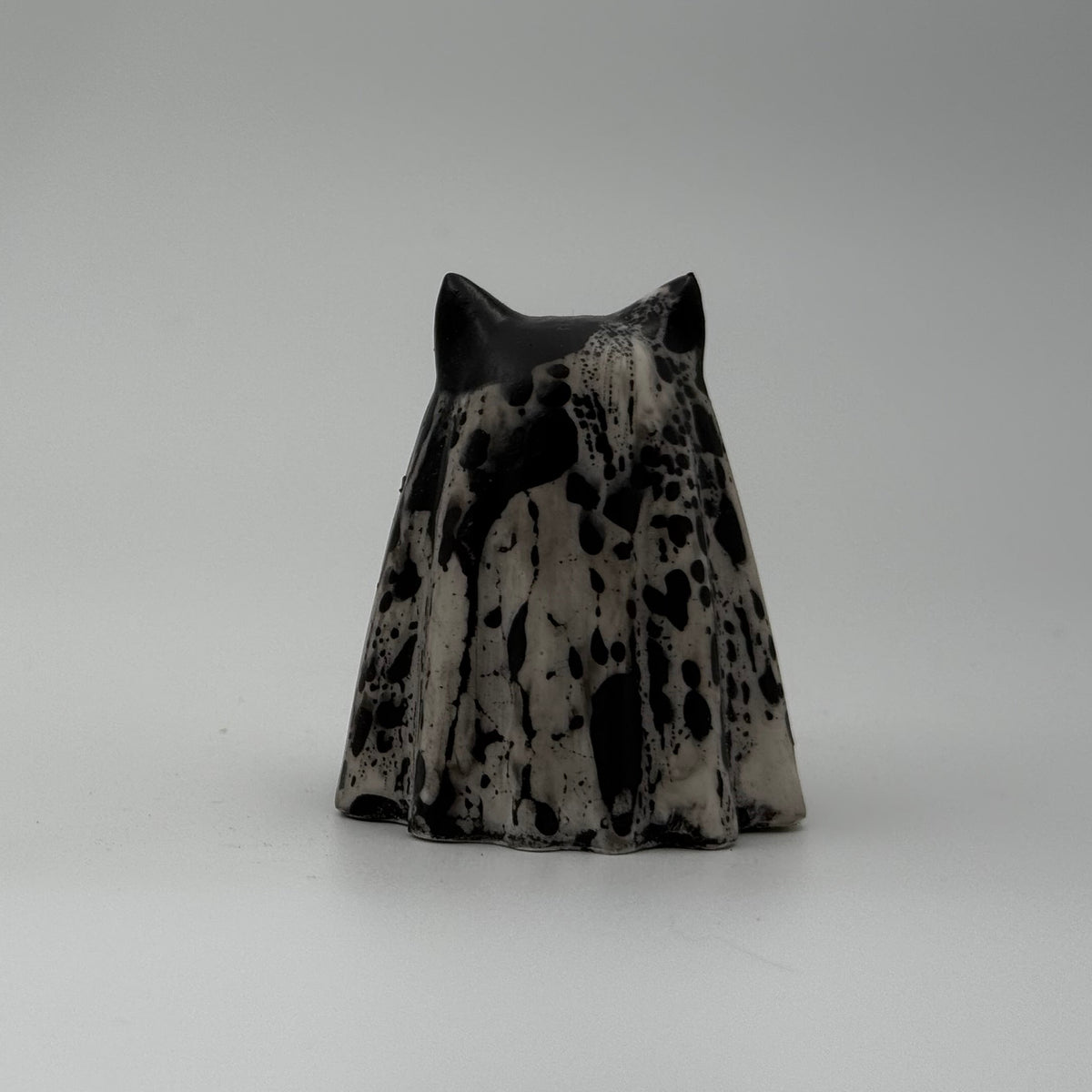 An ivory coloured ghost cat figurine with dramatic black, bark like patterning, by The Nordic Ghost Merchants. Rear view.