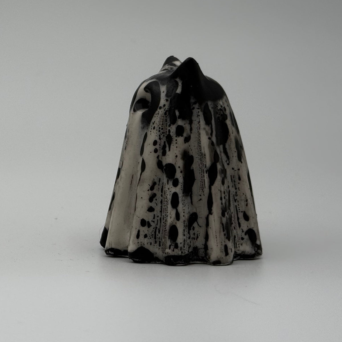 An ivory coloured ghost cat figurine with dramatic black, bark like patterning, by The Nordic Ghost Merchants. Side view.