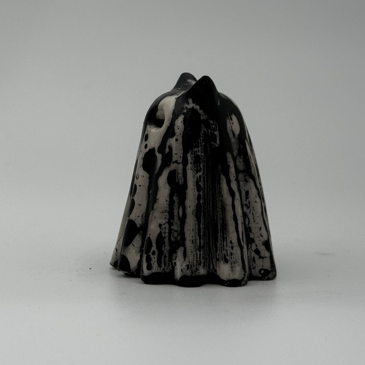 A small white and black coloured ghost cat figurine made by The Nordic Ghost Merchants. Side view