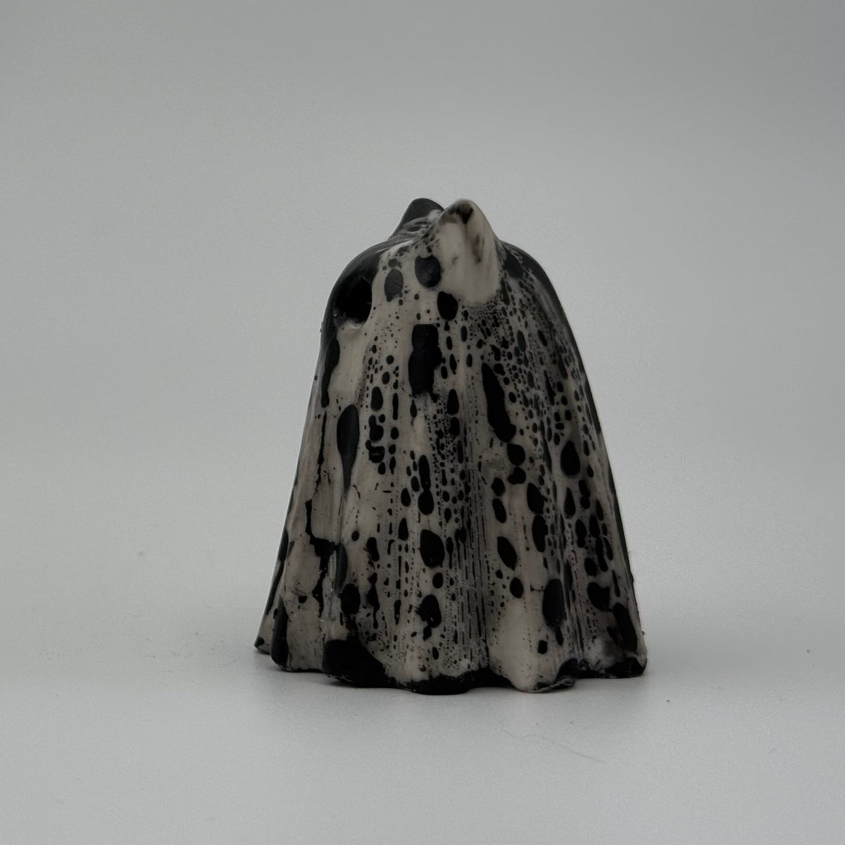 An ivory ghost cat ornament with dramatic black, bark link patterning, made by The Nordic Ghost Merchants. Side view.