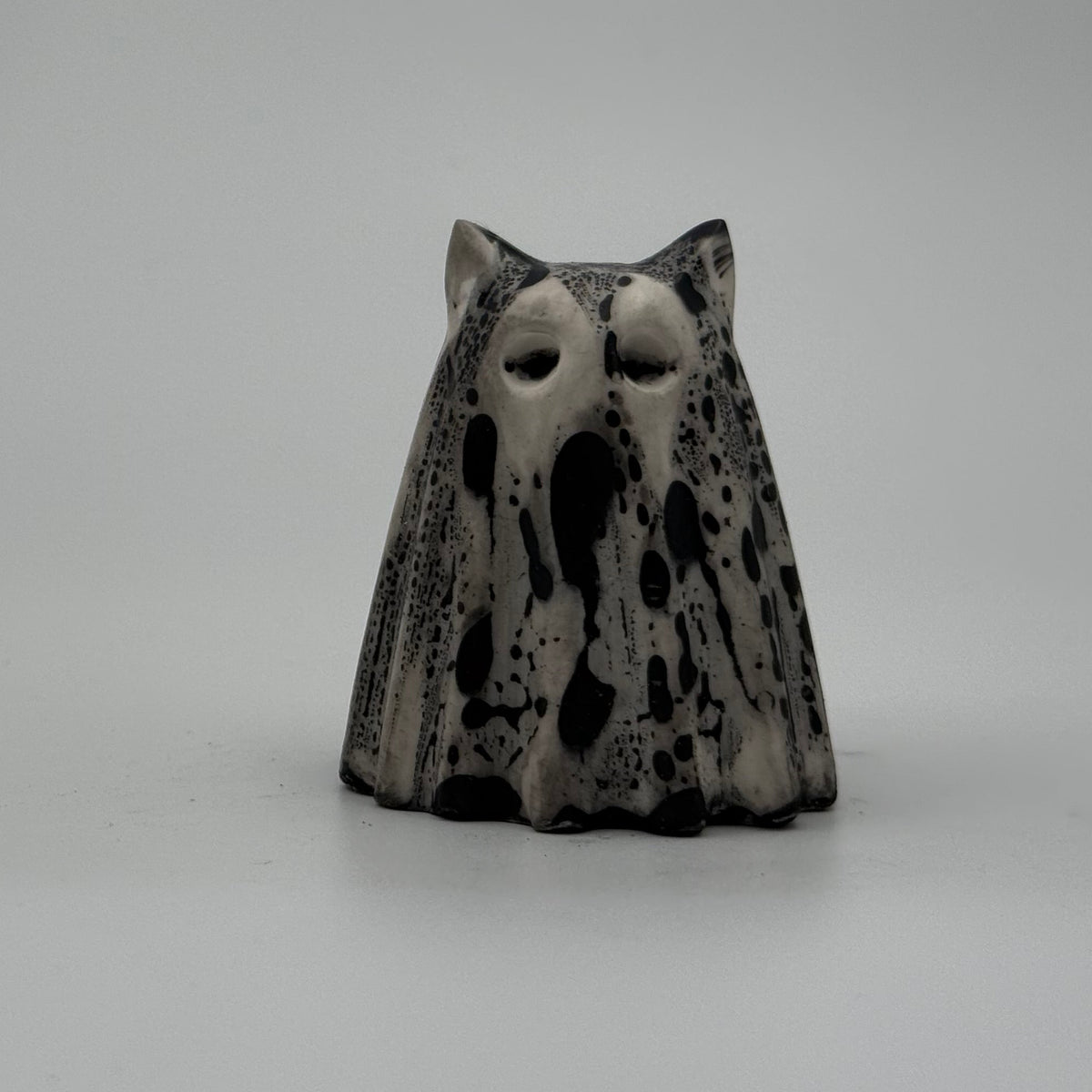 A small white and black ghost cat figurine by The Nordic Ghost Merchants. Front view
