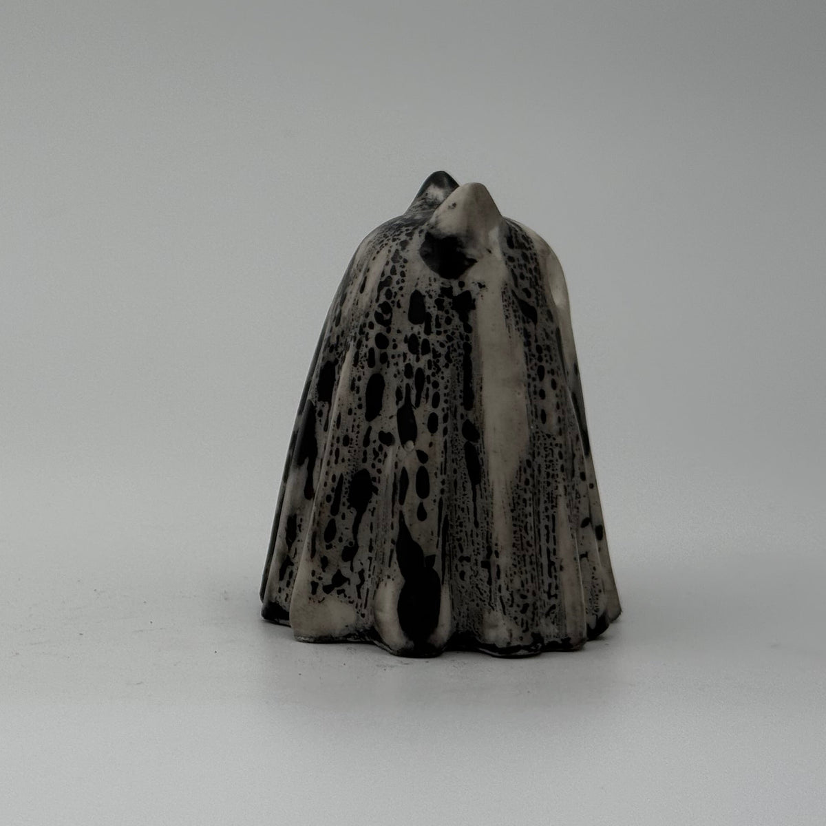 A small white and black ghost cat figurine by The Nordic Ghost Merchants. Side view