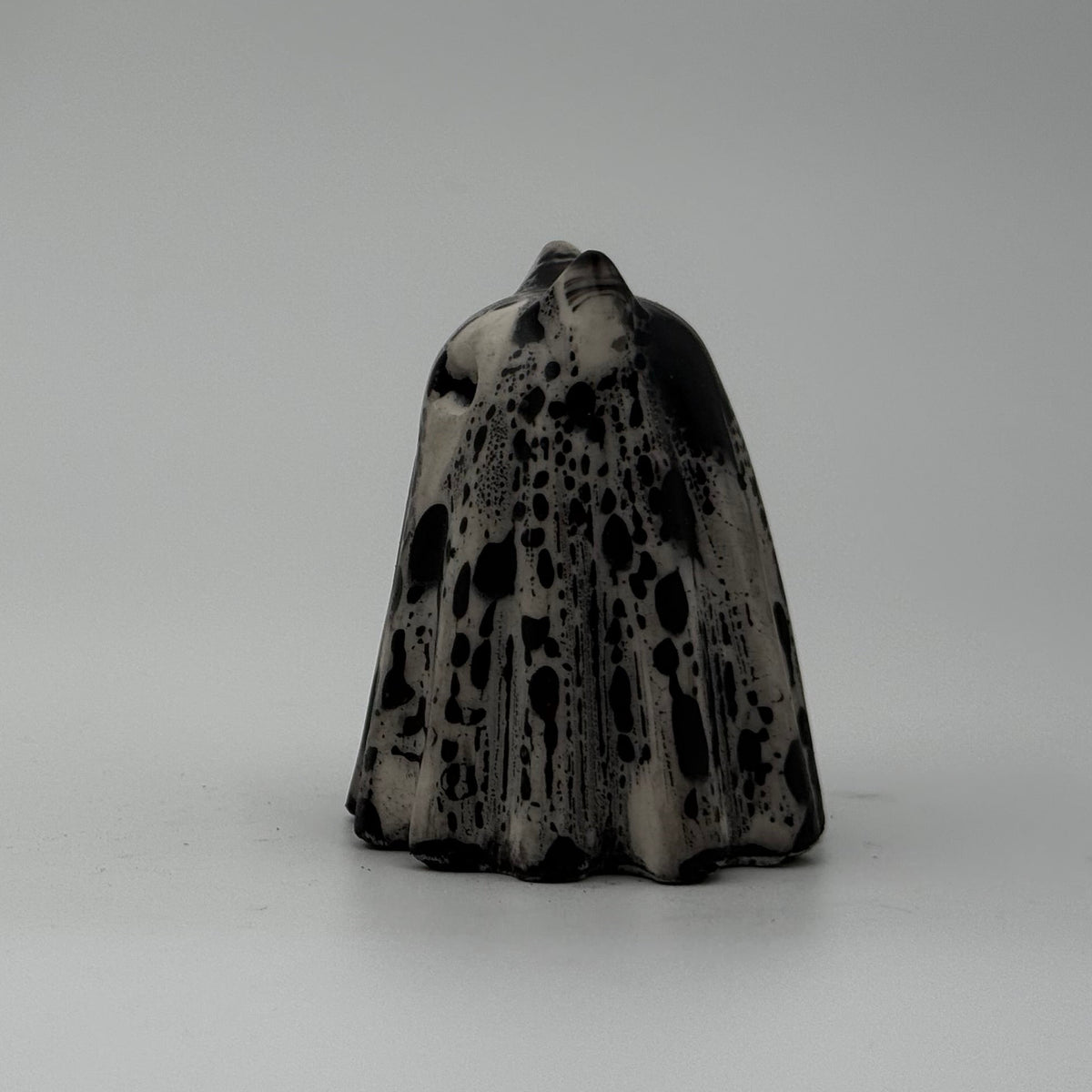 A small white and black ghost cat figurine by The Nordic Ghost Merchants. Side view