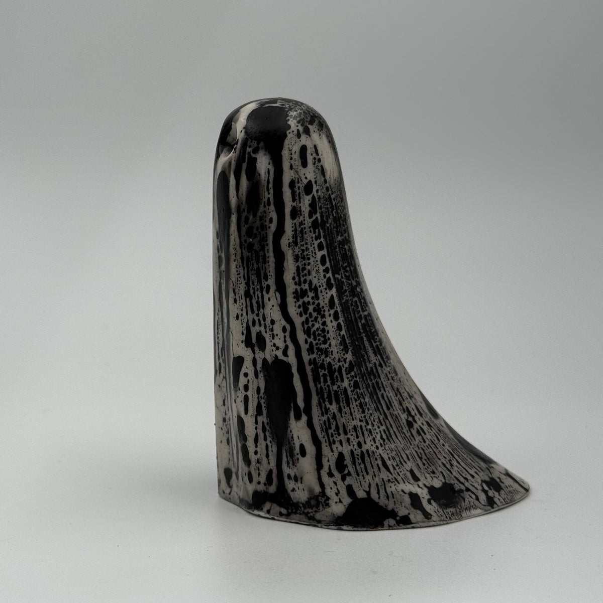 An ivory coloured ghost figurine with black, bark like patterning, made by The Nordic Ghost Merchants. Side view.