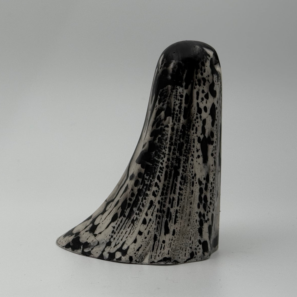 An ivory coloured ghost figurine with black, bark like patterning, made by The Nordic Ghost Merchants. Side view.