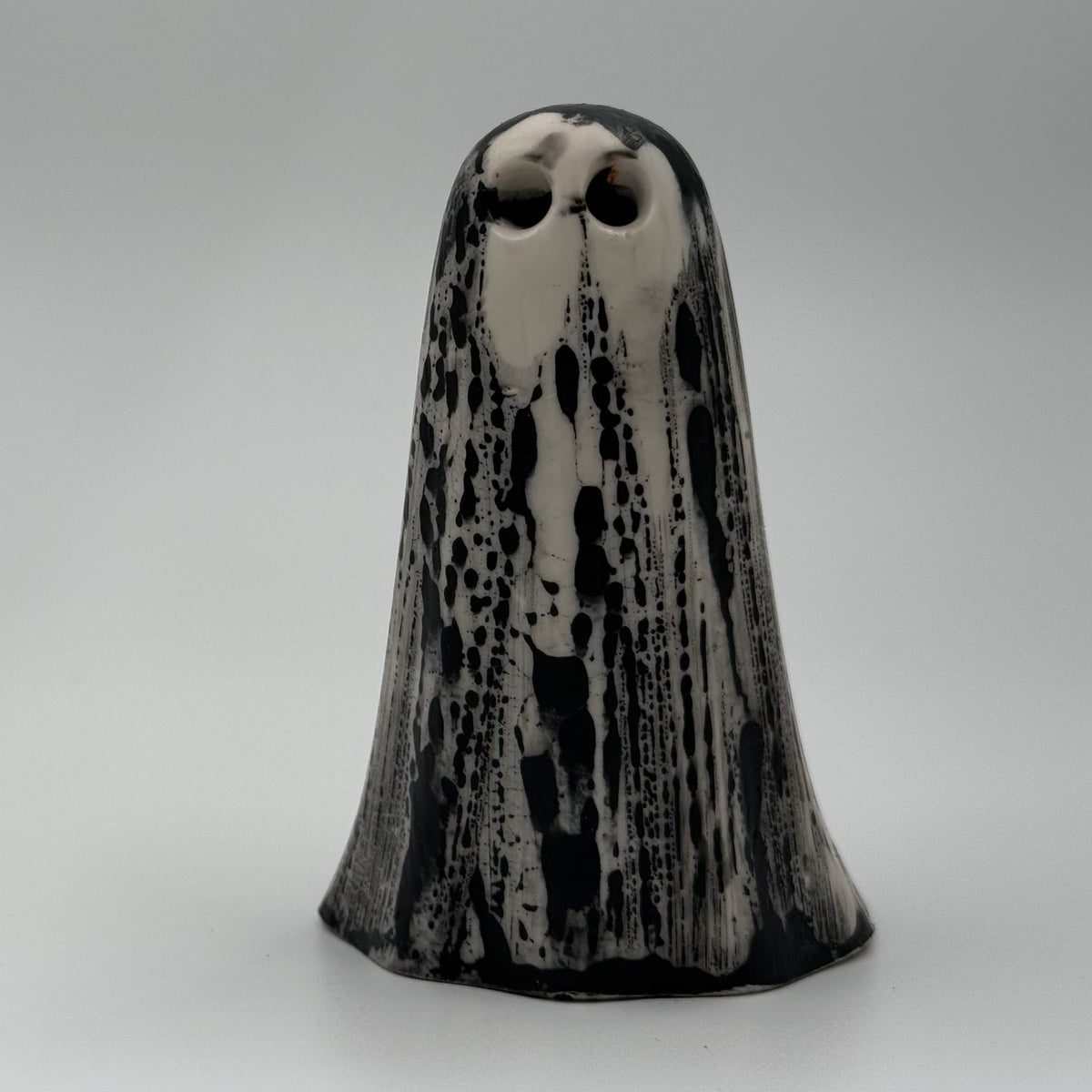 An ivory coloured ghost figurine made by The Nordic Ghost Merchants. The ghost has black, bark like markings.