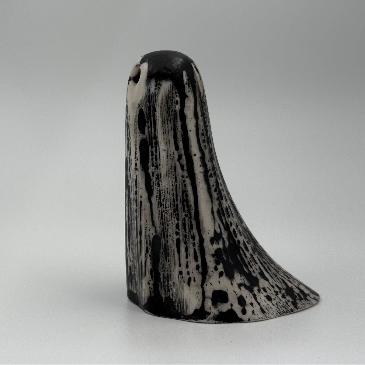 An ivory coloured ghost figurine made by The Nordic Ghost Merchants. The ghost has black, bark like markings.