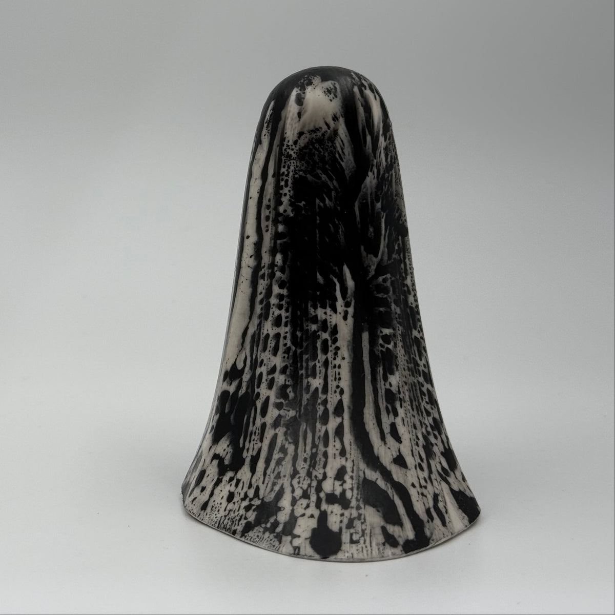 An ivory coloured ghost figurine made by The Nordic Ghost Merchants. The ghost has black, bark like markings.