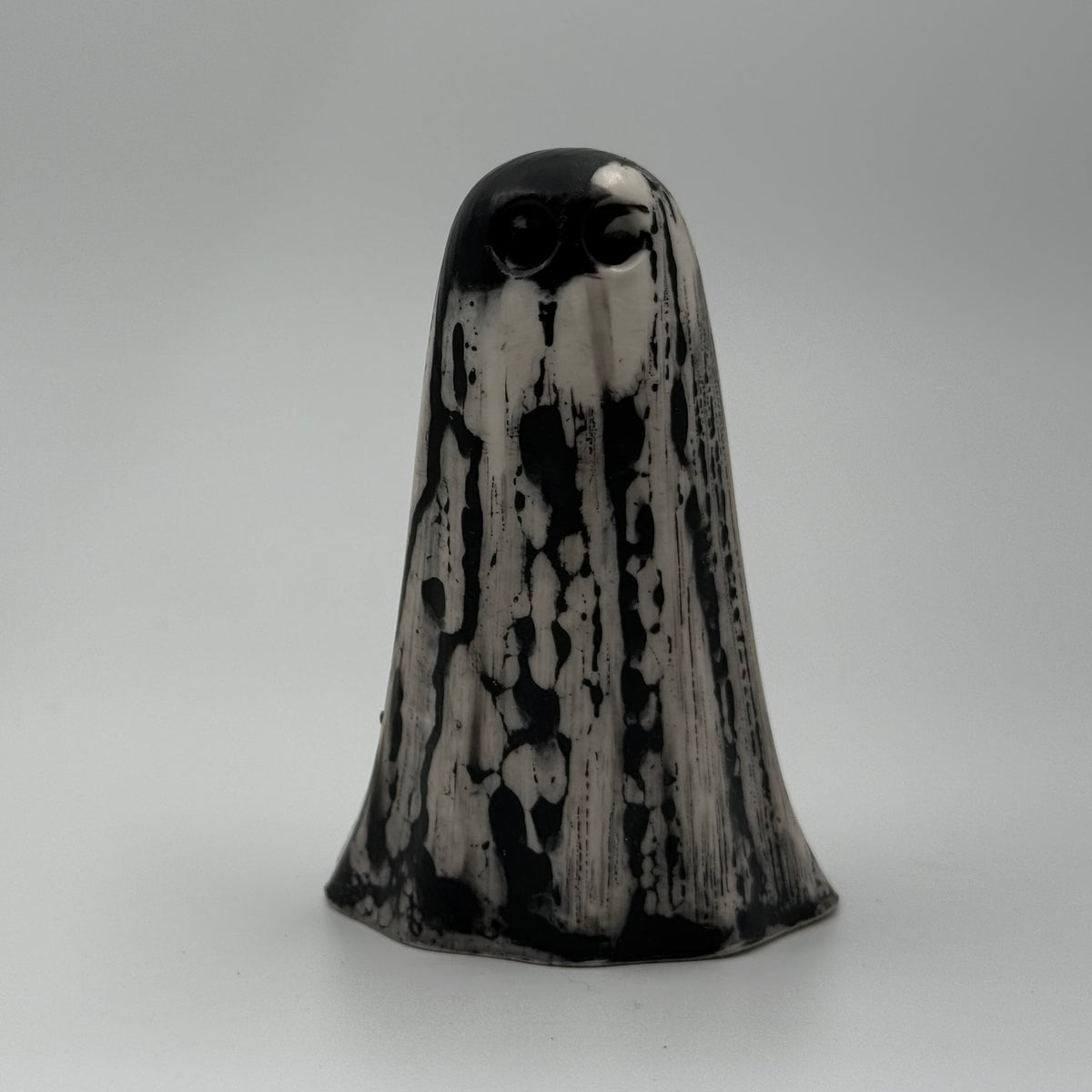 An ivory coloured ghost ornament with dramatic, black, bark like patterning, made by The Nordic Ghost Merchants. Front view
