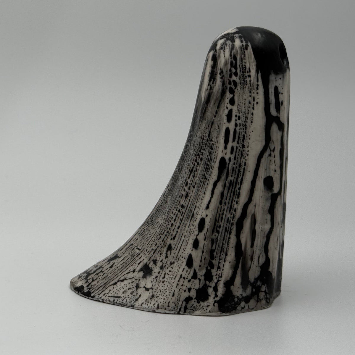 An ivory coloured ghost ornament with dramatic, black, bark like patterning, made by The Nordic Ghost Merchants. Side view