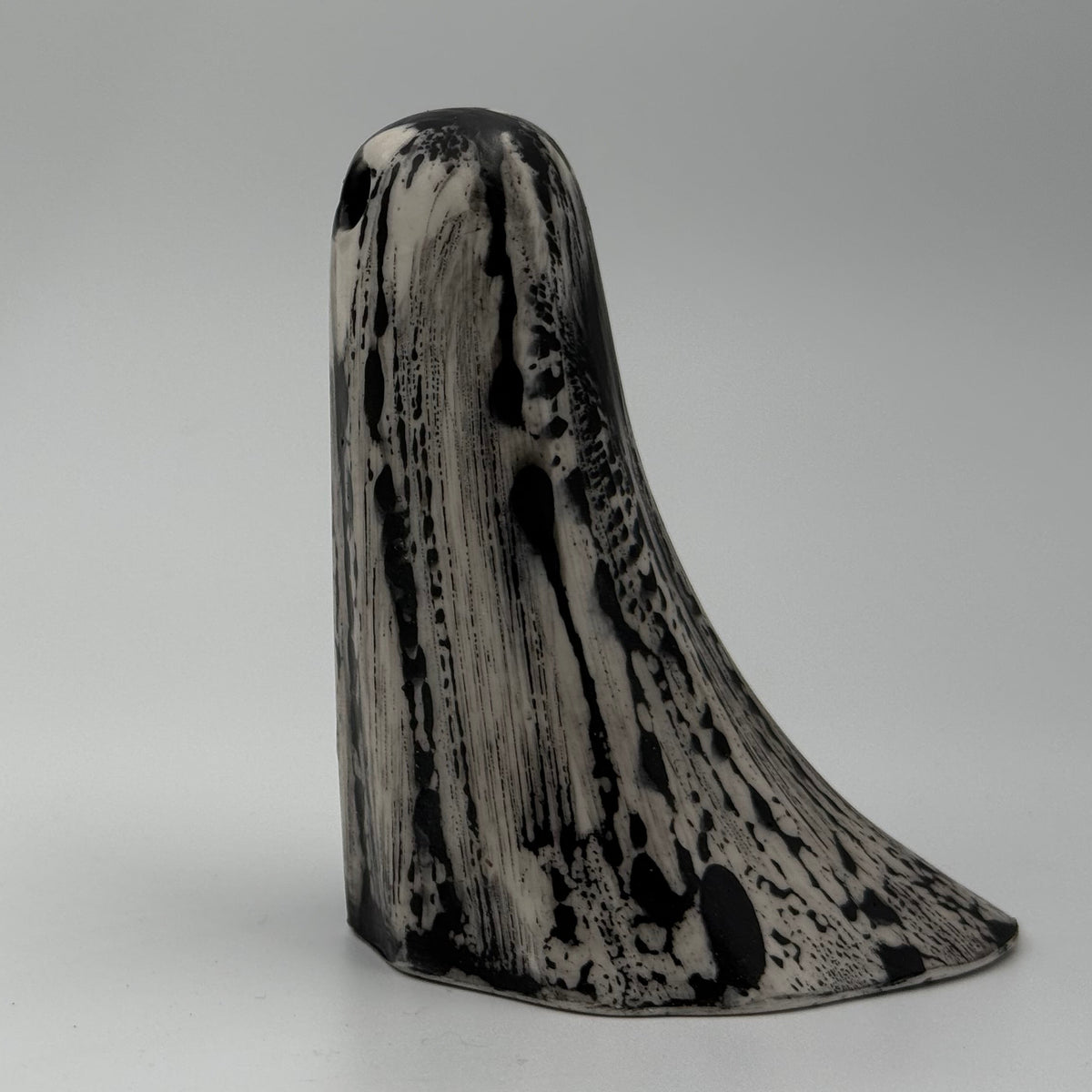 An ivory coloured ghost ornament with dramatic, black, bark like patterning, made by The Nordic Ghost Merchants. Side view