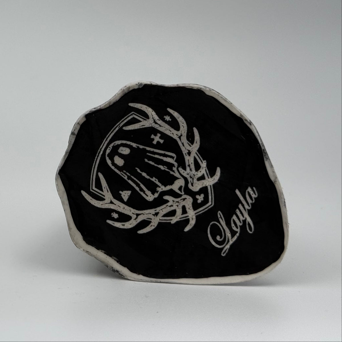 An ivory ghost figurine with dramatic black, bark like patterning, made by The Nordic Ghost Merchants. Base view.