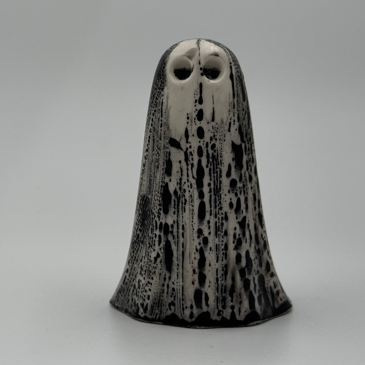 An ivory ghost figurine with black bark like patterning made by The Nordic Ghost Merchants. Front view.