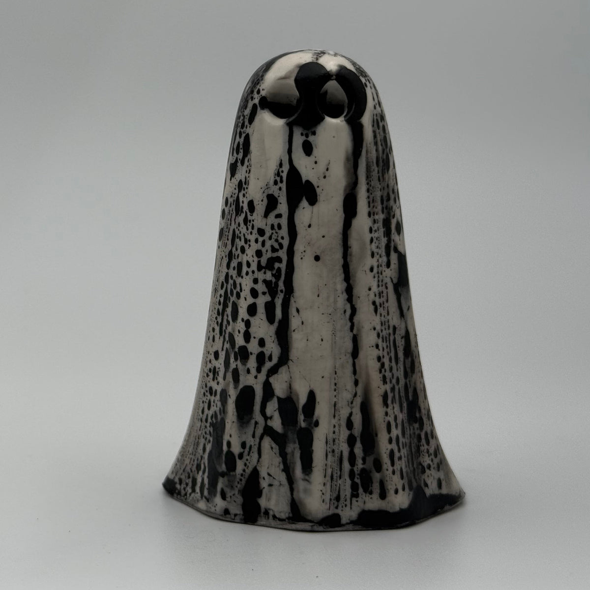 An ivory coloured ghost ornament with dramatic, black bark like patterning, made by The Nordic Ghost Merchants. Front view.