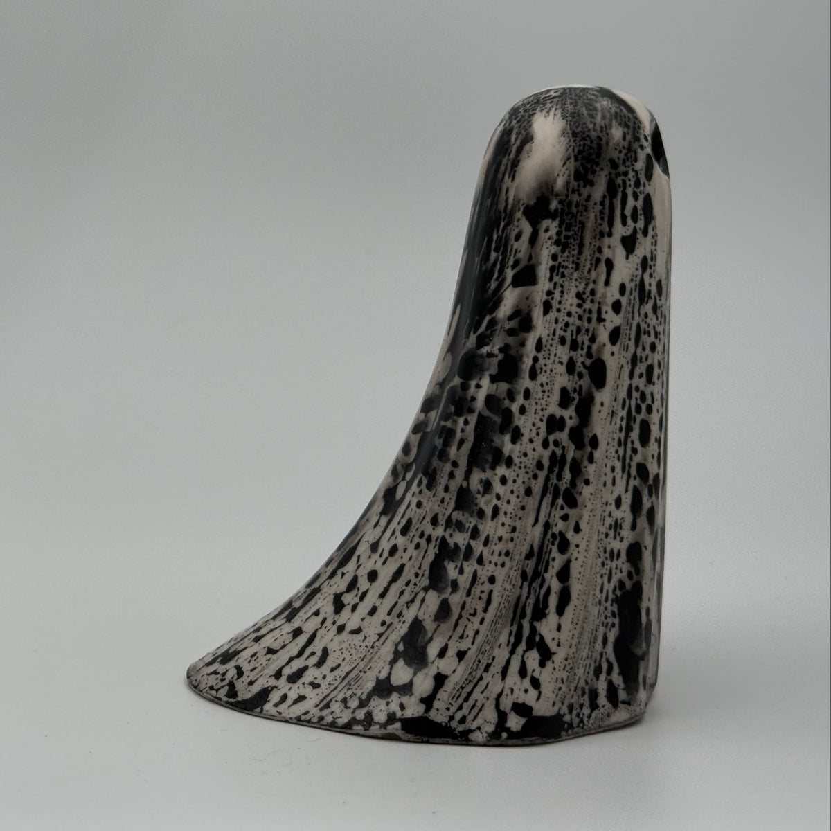 An ivory coloured ghost ornament with dramatic, black bark like patterning, made by The Nordic Ghost Merchants. Side view.