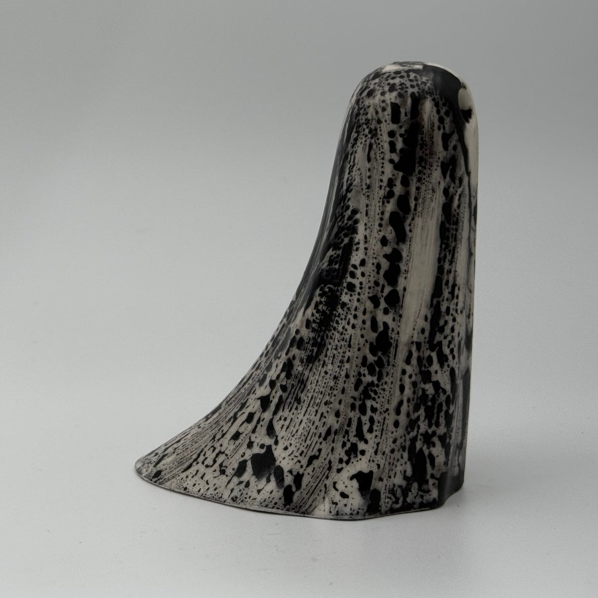 An ivory ghost ornament with dramatic black, bark like patterning, made by The Nordic Ghost Merchants. Side view