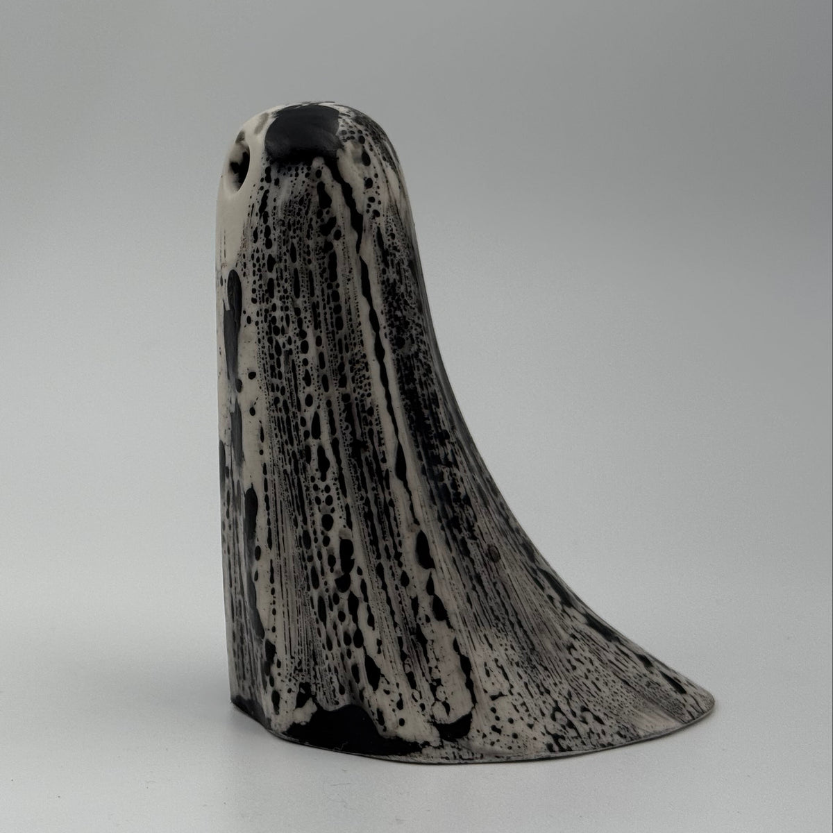 An ivory ghost ornament with dramatic black, bark like patterning, made by The Nordic Ghost Merchants. Side view