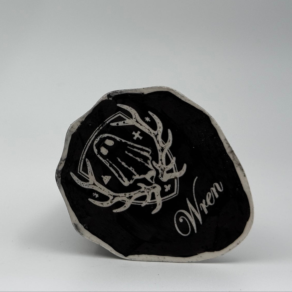 An ivory ghost ornament with dramatic black, bark like patterning, made by The Nordic Ghost Merchants. Base view