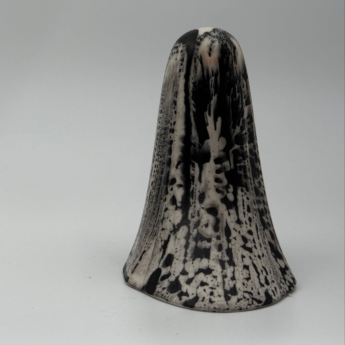 An ivory coloured ghost ornament with dramatic, black bark like patterning, made by The Nordic Ghost Merchants. Rear view.