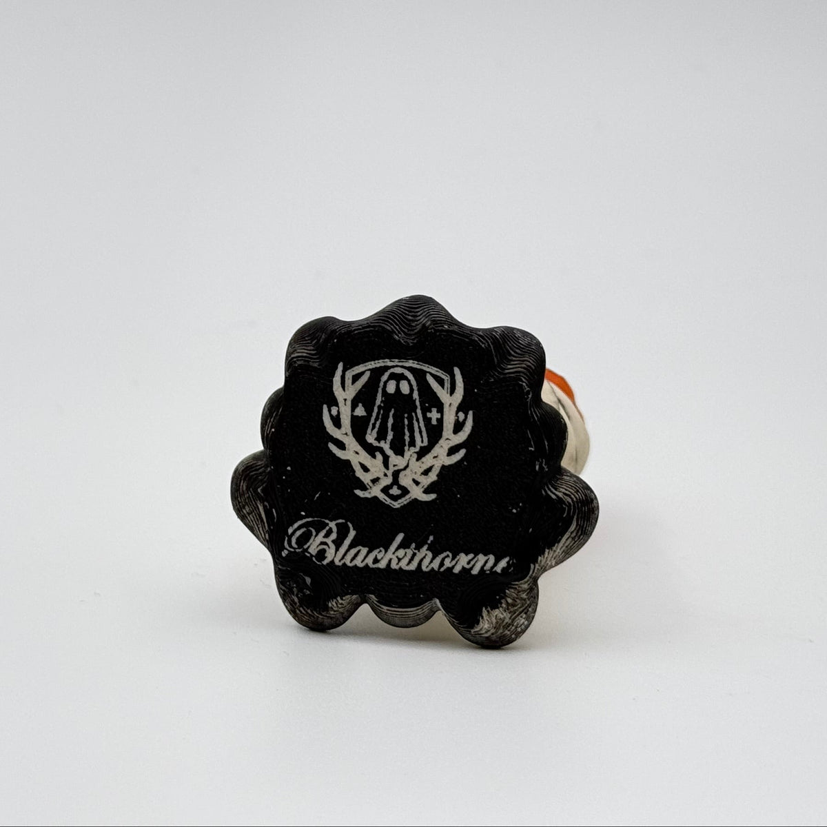 A hand painted folklore figurine made by The Nordic Ghost Merchants in Denmark. The image shows the base of the folklore ornament, painted black and engraved with the brand logo - a coat of arms with a sheet ghost in the centre.